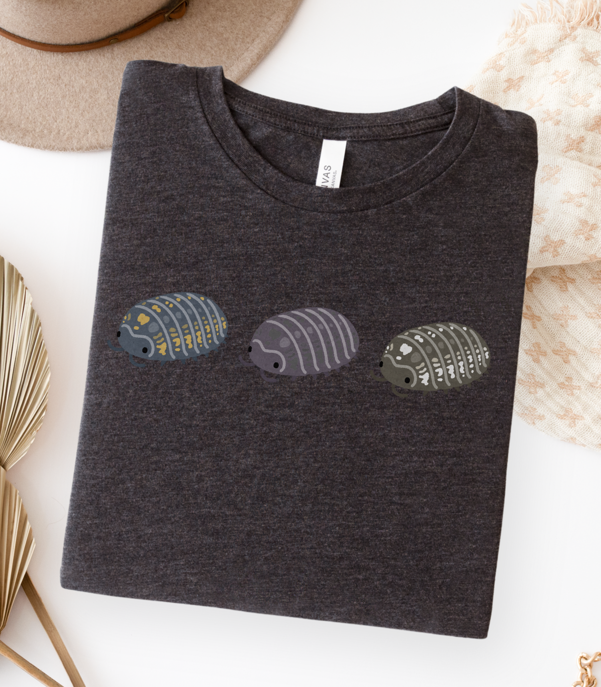 A folded dark grey heather t-shirt with a graphic of three stylized isopods in blue and yellow, purple, and black and white.
