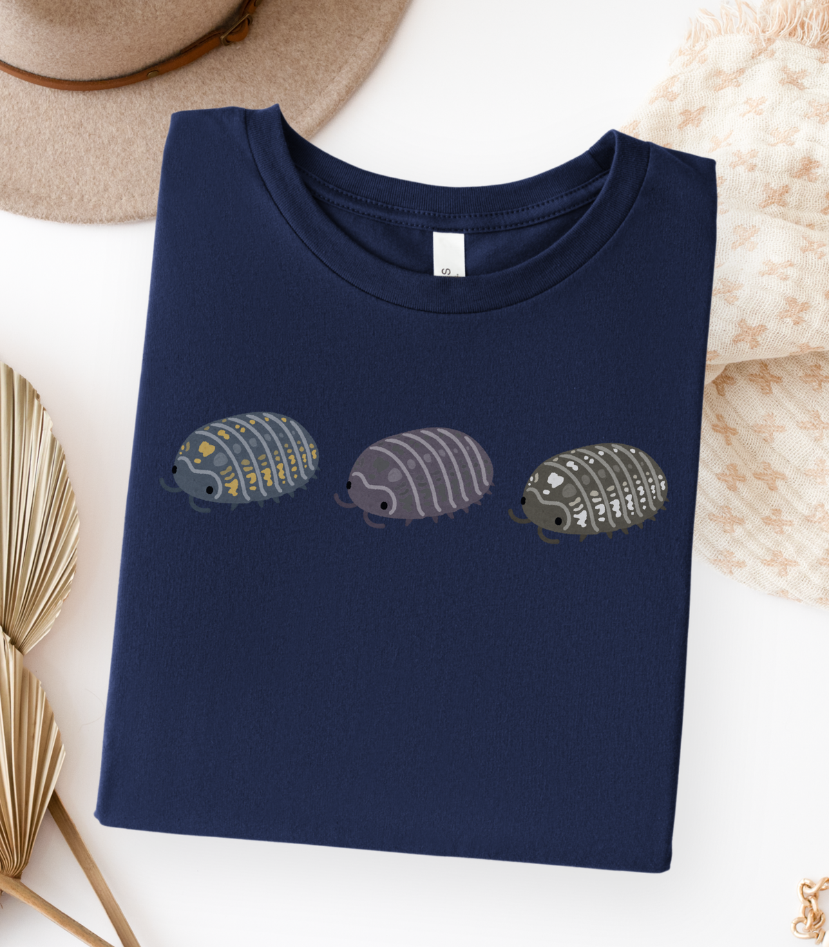 A folded navy blue t-shirt with a graphic of three stylized isopods in blue and yellow, purple, and black and white.